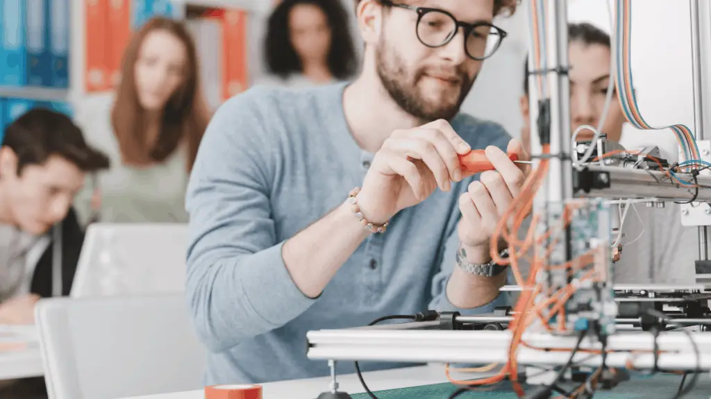 man tinkering with 3d printer